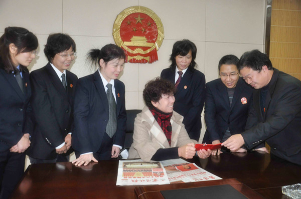 端详着党的十八大代表证书和出席证,敖大焕与法官们一起分享参加十八大的喜悦。_副本.jpg